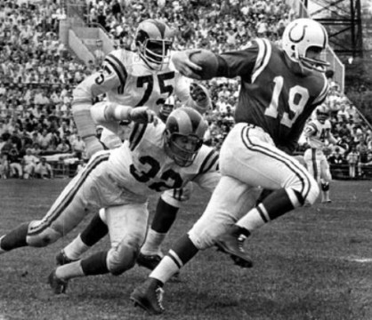 Baltimore Colts legend Johnny Unitas is forced to flee under the pressure of Los Angeles Ram defenders Jack Pardee (#32) and Deacon Jones (#75). 
