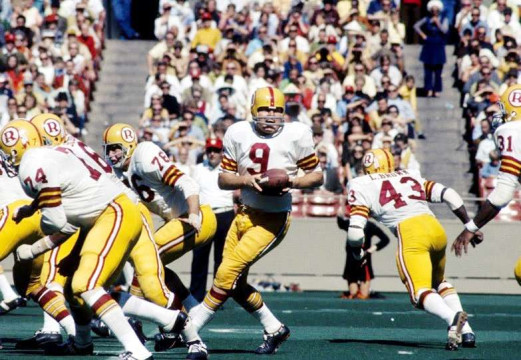 Redskins quarterback Sonny Jurgensen (#9) gets set behind his offensive line as runningbacks Larry Brown (#43) and Charley Harraway (#31) move into position.