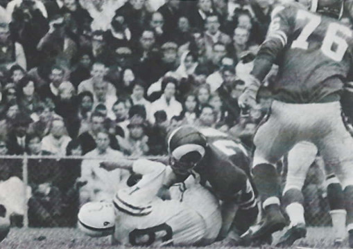 Down goes Colts quarterback Johnny Unitas (#19) under the weight of Rams lineman Merlin Olsen (#74) and Rosey Grier (#76)