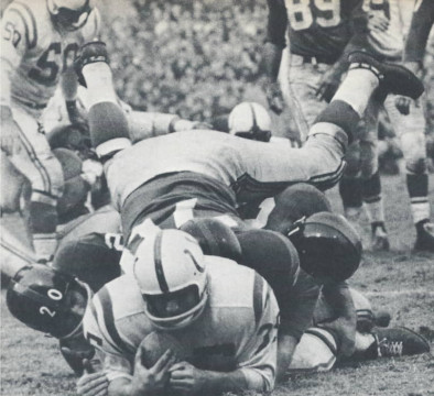 Despite the efforts of Jimmy Patton (#20), Sam Huff (#70) and an additional Giant Colt runner Alan Ameche still makes forward progess against the New York defense. Center Buzz Nutter (#50) and defensive end Cliff Livingston (#89) are seen in the background.