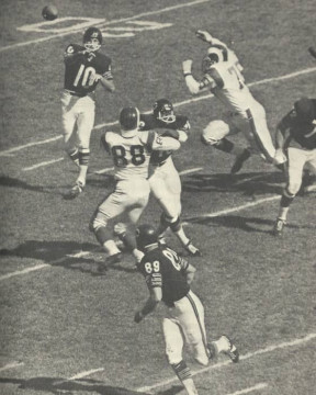 Bears quarterback Rudy Bukich (#10) gets the pass off to Mike Ditka (#89) as Rams Hall of Famer Deacon Jones (#75) comes in full steam. Ram #88 is linebacker Tony Guillory.
