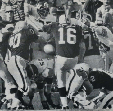 George Blanda kicks a 27-yard field goal against the Steelers in 1970. It was this game he came off the bench and threw 3 touchdowns in addition to this field goal to help the Raiders win 31-14. Some big names in this picture - We see Jim Otto (#00) barring the way of Joe Greene (#75) and former Chargers standout Chuck Allen (#58) while Rookie Ken Stabler (#12) holds for Blanda.