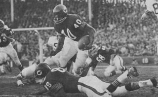 Chicago Bears runner Gale Sayers hurdles over Mike Ditka