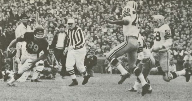 A black and white photo of a football game featuring Mike Ditka making a catch against Green Bay Packers players in 1963.