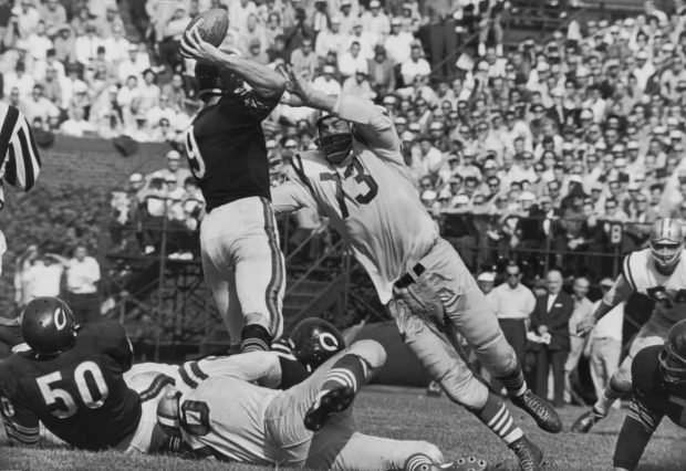 Black and white photo taken by Rob Riger of Leo Nomellini rushing Bear quarterback Billy Wade.