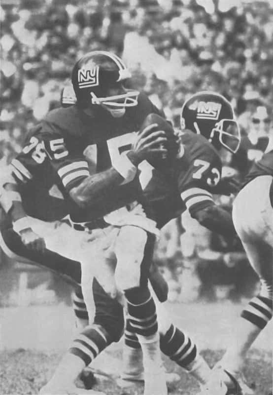 A black and white image of Craig Morton, dropping back to pass with Tom Mullen blocking for him during a game.