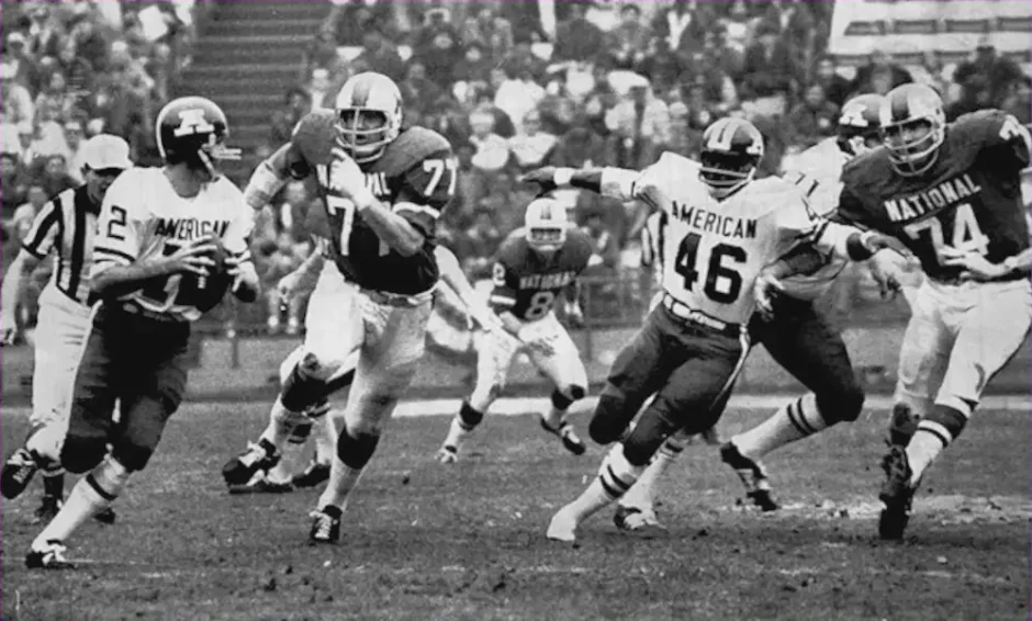 In 1971 the NFL's Pro Bowl featured the best players from the newly merged league. The NFL now consisted of the National and American Football conferences. Here Bob Griese (dolphins) and Floyd Little (Broncos) execute a pass play against Gary Larsen (Vikings) and Bob Lilly (Cowboys). Larry Wilson (Cardinals) can be seen in the background. The NFC would win the first Pro Bowl 27-6.