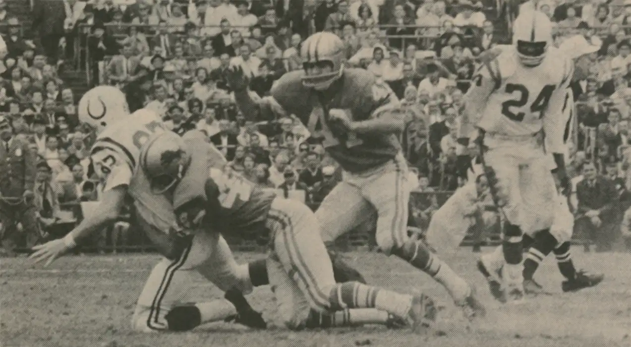 The Colts receiving legend Ray Berry is brought down by Lions defensive legend Dick LeBeau. In 1965, Berry, at 32 years old, was the Colts leading receiver with 58 catches while LeBeau had the second most interceptions in the league with 7. Lions Safety Wayne Rasmussen along with Colt Lenny Moore are also seen.