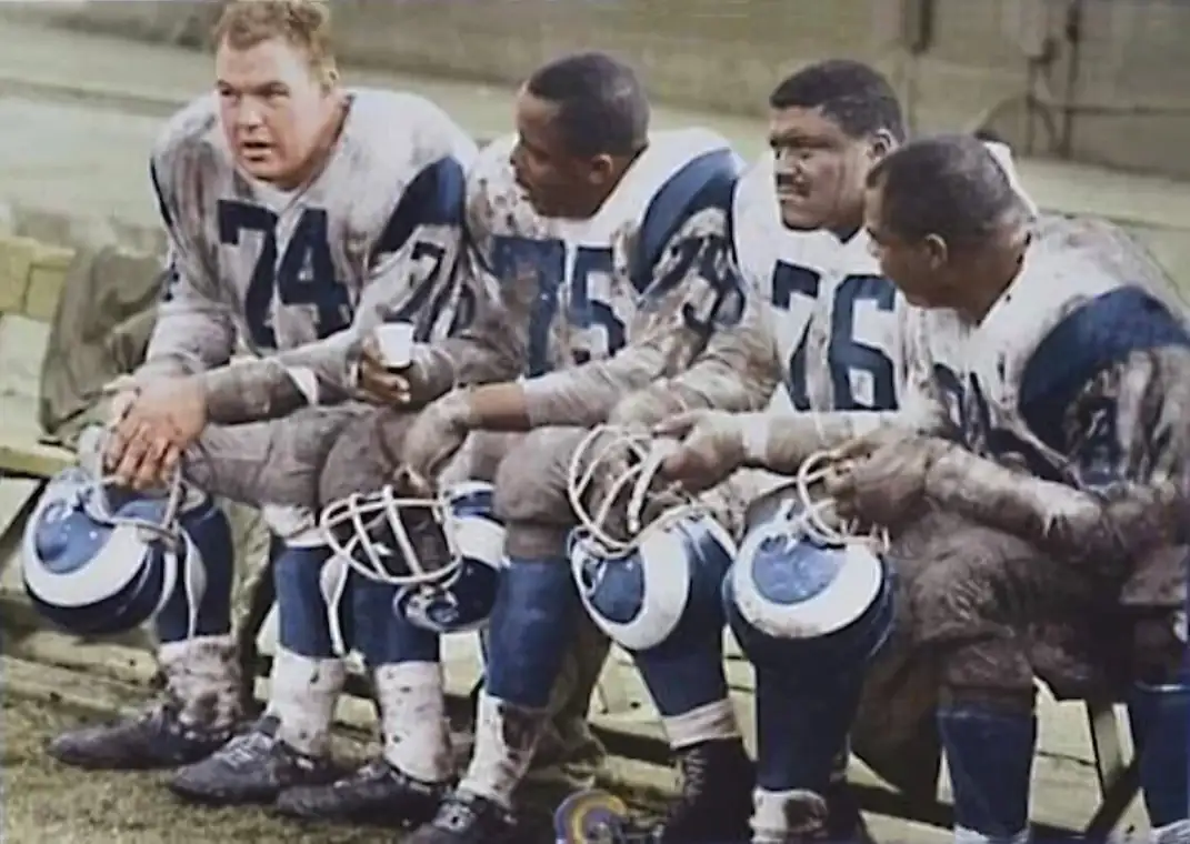 The legendary “Fearsome Foursome” of the Los Angeles Rams—Merlin Olsen, Deacon Jones, Rosie Grier, and Lamar Lundy—pause together on the sideline, a rare moment of calm for one of the most dominant defensive units in NFL history. During the late 1960s and early 1970s, this Rams front four redefined defensive line play, combining speed, strength, and relentless pressure to overwhelm opposing offenses.
Deacon Jones, widely credited with coining the term “sack,” terrorized quarterbacks off the edge, while Merlin Olsen anchored the interior with consistency and intelligence. Flanked by the powerful Rosie Grier and the versatile Lamar Lundy, the group formed a near-unstoppable force that became the identity of the Rams defense during their rise as perennial contenders.
More than just stars, the Fearsome Foursome helped shape the modern pass rush, setting a standard for defensive dominance that still echoes throughout the game today.