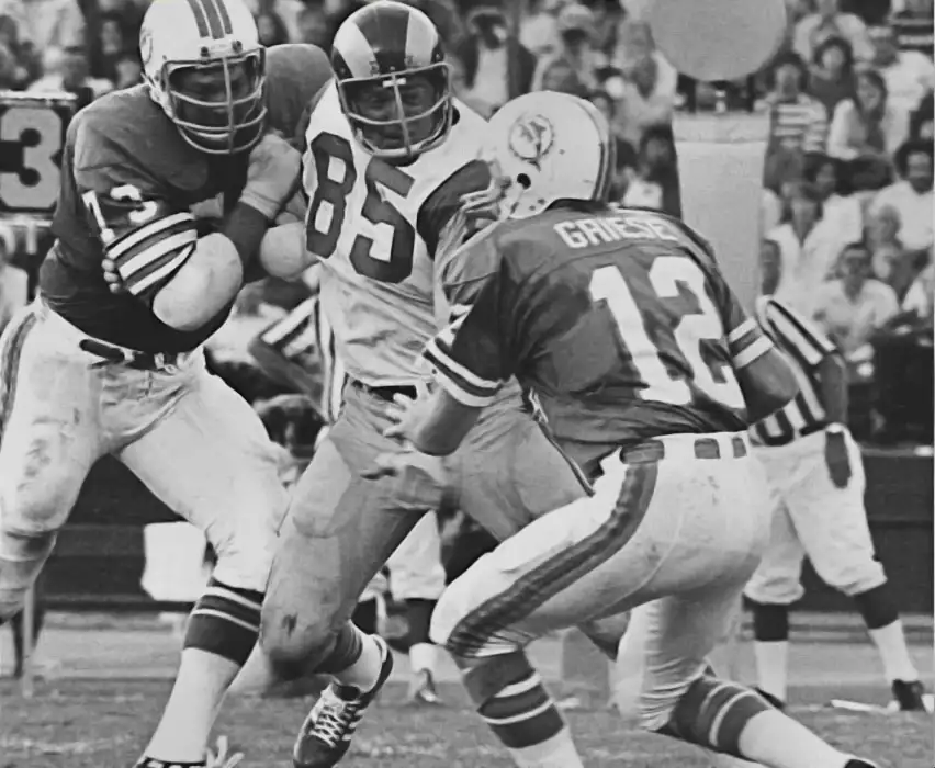 Dolphins lineman Norm Evans is having a bit of difficulty keeping Jack Youngblood off of quarterback Bob Griese in this 1970s-era NFL picture. "Unofficially" Youngblood has been credited with 151½ sacks in his 14-year NFL career.
