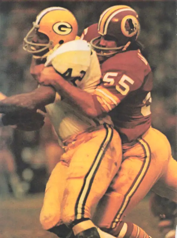 John Brockington gets wrapped up by Redskin linebacker Chris Hanburger in an early 1970s NFL game.